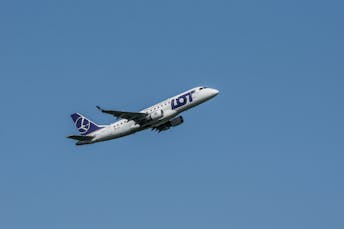 LOT Polish Airlines plane flying against a clear blue sky, showcasing modern aviation.
